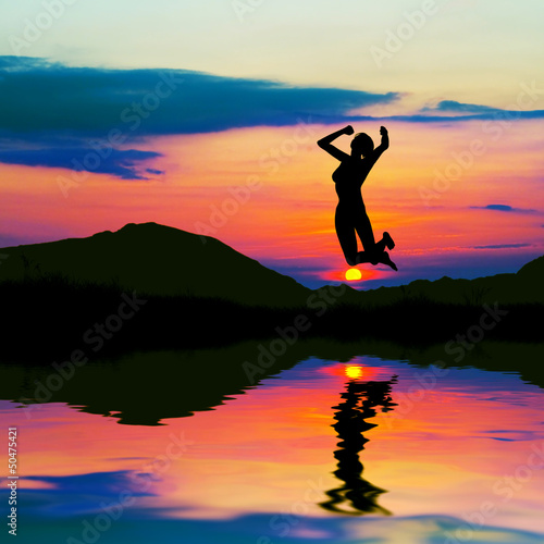 Silhouette of a happy woman jumping for joy at sunset.