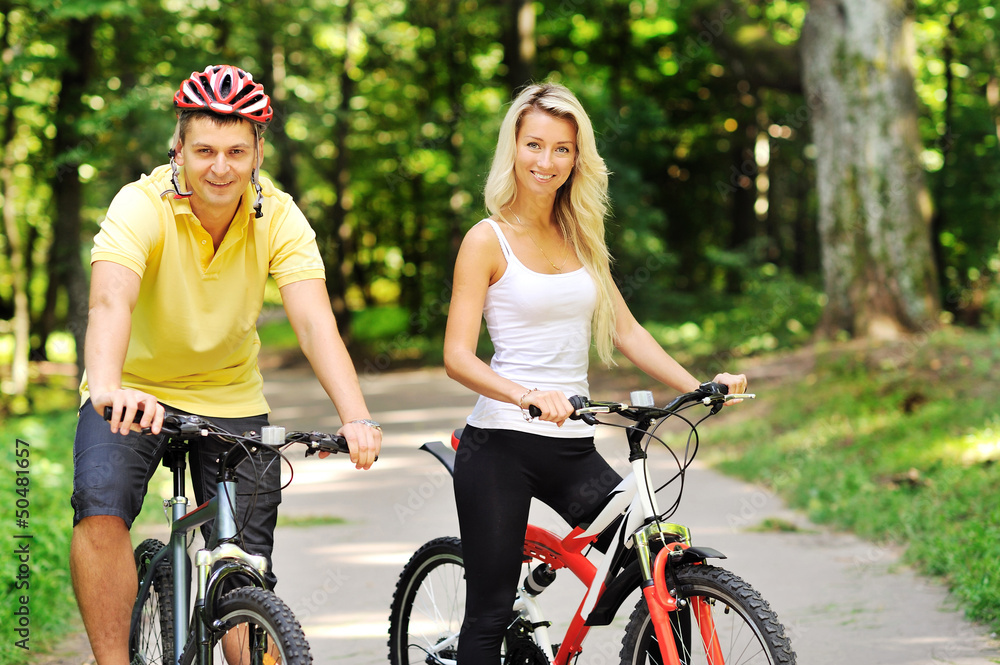 Naklejka premium Attractive happy couple on a bicycles in a countryside