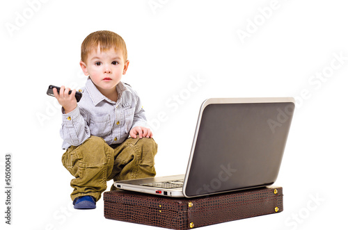 Beautiful boy with a mobile phone is sitting next to a laptop