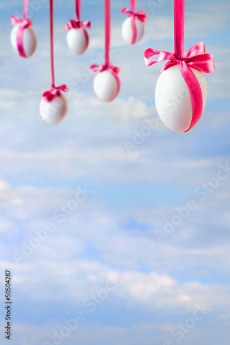Easter card with empty space and eggs hanged on the ribbons