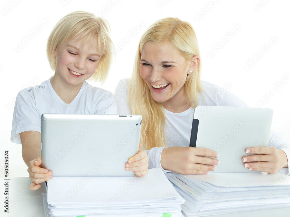 Two pupils leaning on a stack of paper while reading on touchpad Two pupils leaning on a stack of paper while reading on touchpad