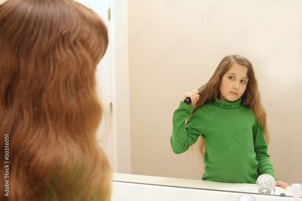 Fototapeta premium Girl looks at her reflection while getting ready