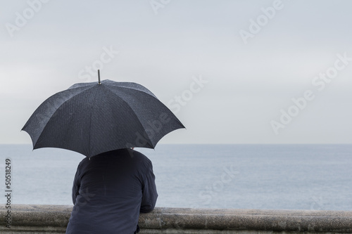 Hombre con paraguas apoyado en balustrada © Marco Antonio Fdez.