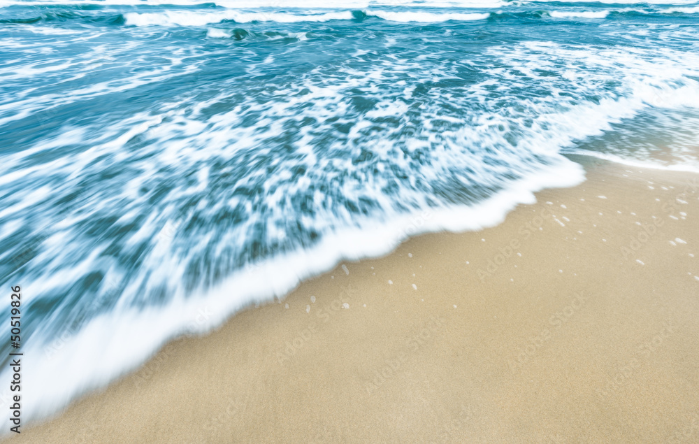Blue ocean waves background with golden sand.