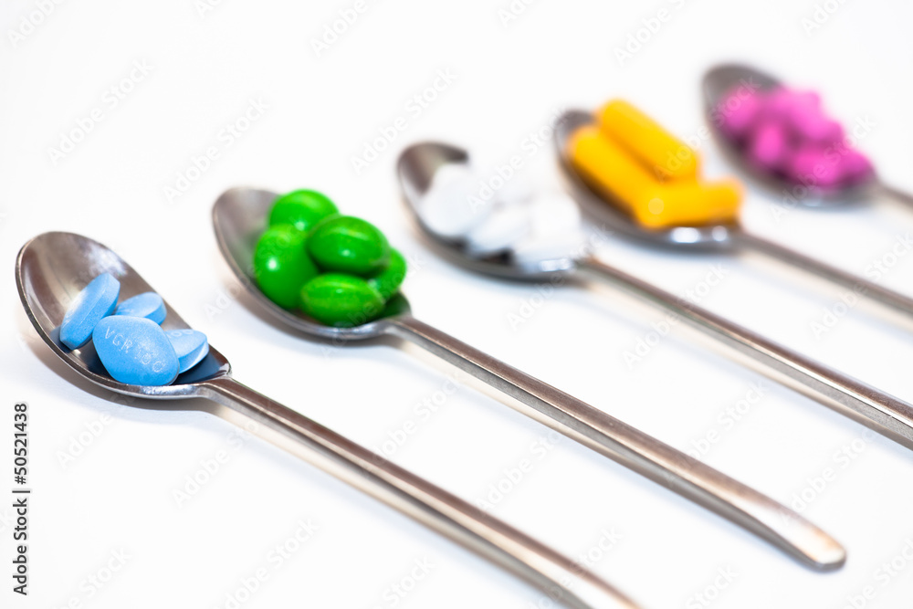 Bunte Tablettenmischung auf Löffeln Bunte Tablettenmischung auf Löffeln