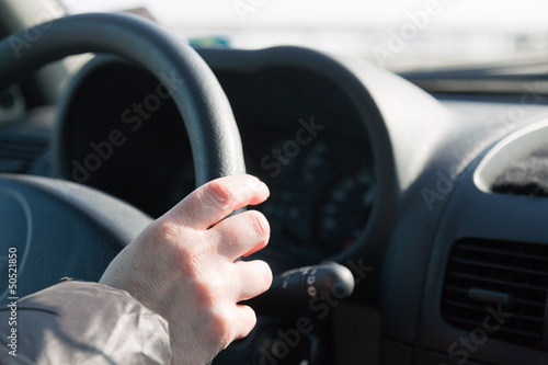 Womans hand on steering wheel of car. Driving woman.