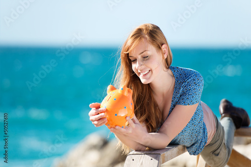 junge frau mit sparschwein am meer photo