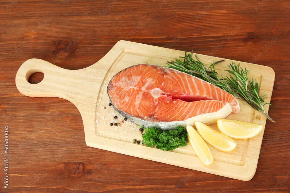 Fresh salmon steak on cutting board, on wooden background Fresh salmon steak on cutting board, on wooden background