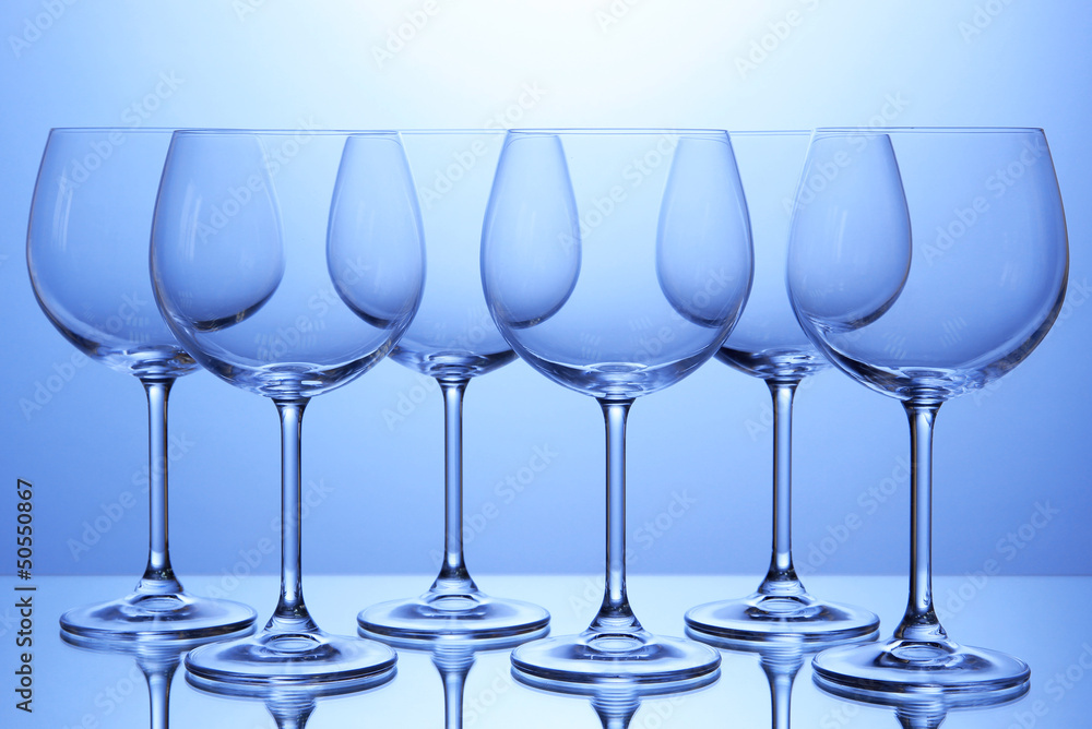 Empty wine glasses arranged on blue background Empty wine glasses arranged on blue background