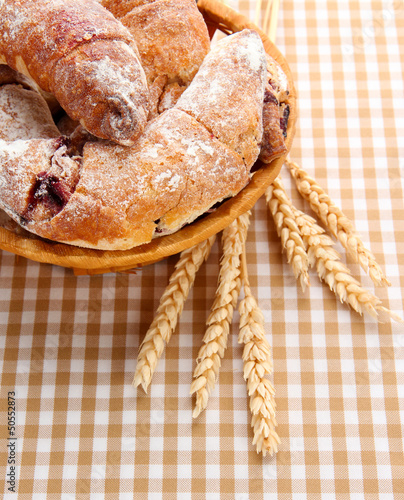 Taste croissants in basket on tablecloth.