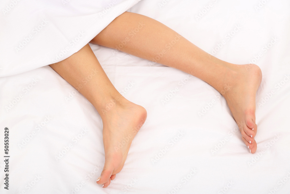 Beautiful feet of a young woman lying in bed close up