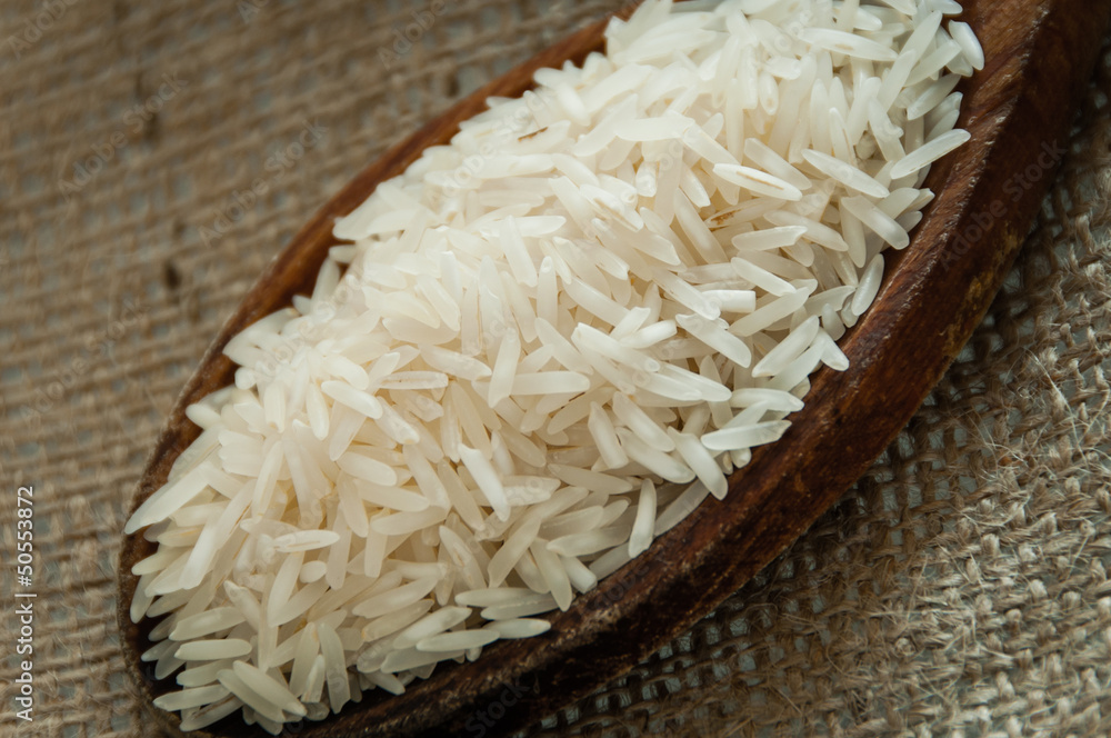 Wooden spoon with rice isolated on Jute background Wooden spoon with rice isolated on Jute background
