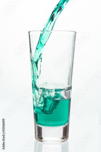Glass being filled with green liquid