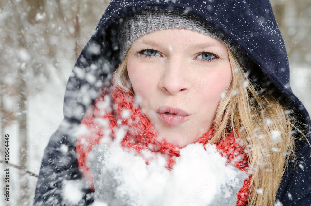 junge blonde Frau pustet in einen handvoll Schnee junge blonde Frau pustet in einen handvoll Schnee