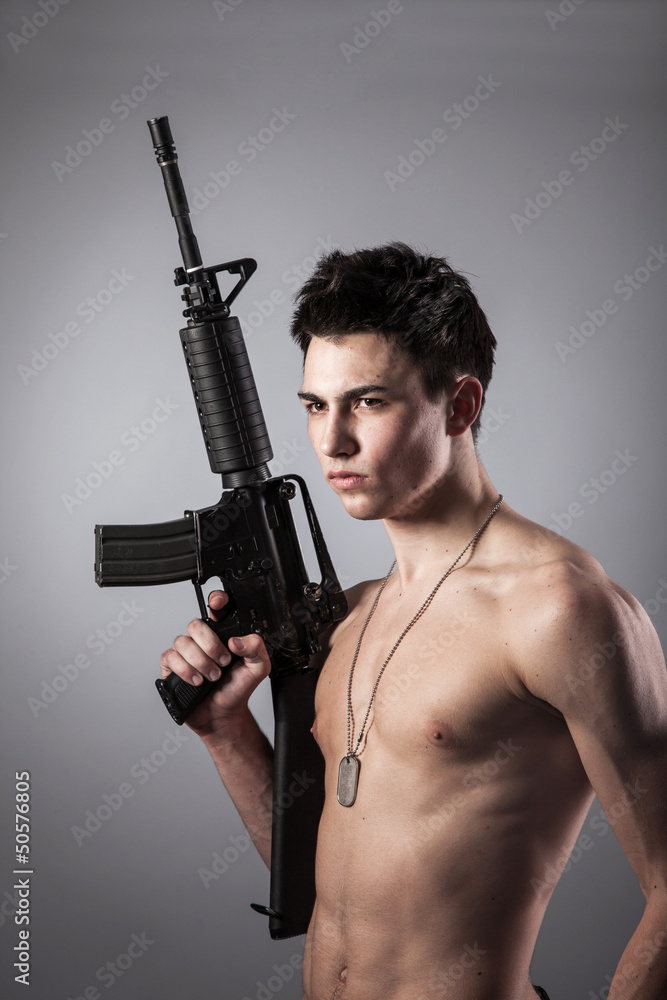 Handsome bare-chested soldier is holding a rifle Handsome bare-chested soldier is holding a rifle
