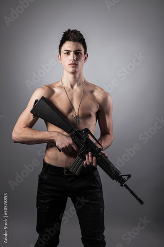 Handsome bare-chested soldier is holding a rifle