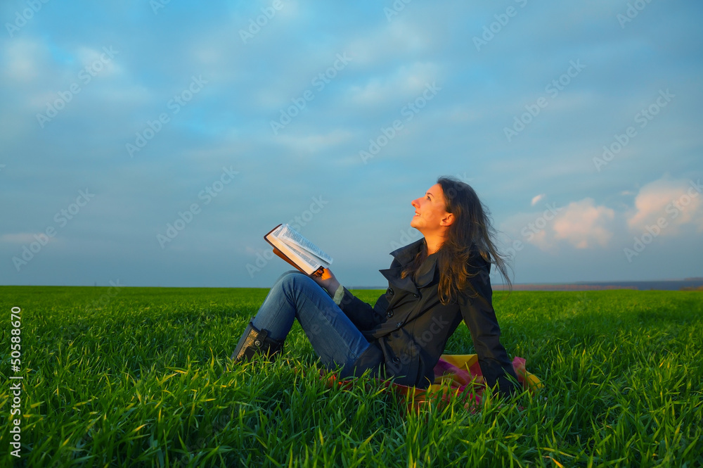 Teen girl reading the Bible outdoors