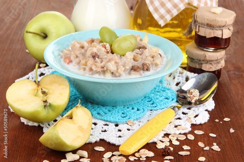 Useful oatmeal in bowl with fruit on wooden table close-up