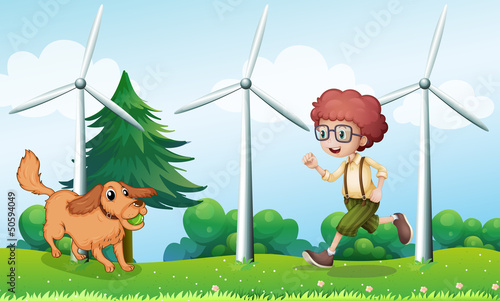 A boy playing with his dog near the windmill