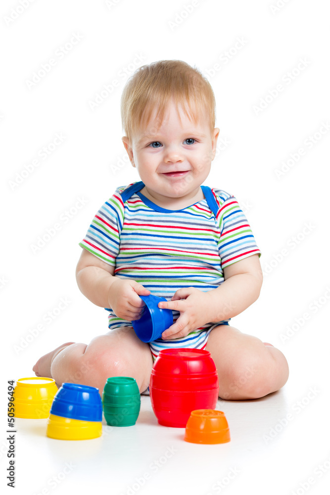Cute baby boy playing with toys while sitting on floor, isolated Cute baby boy playing with toys while sitting on floor, isolated