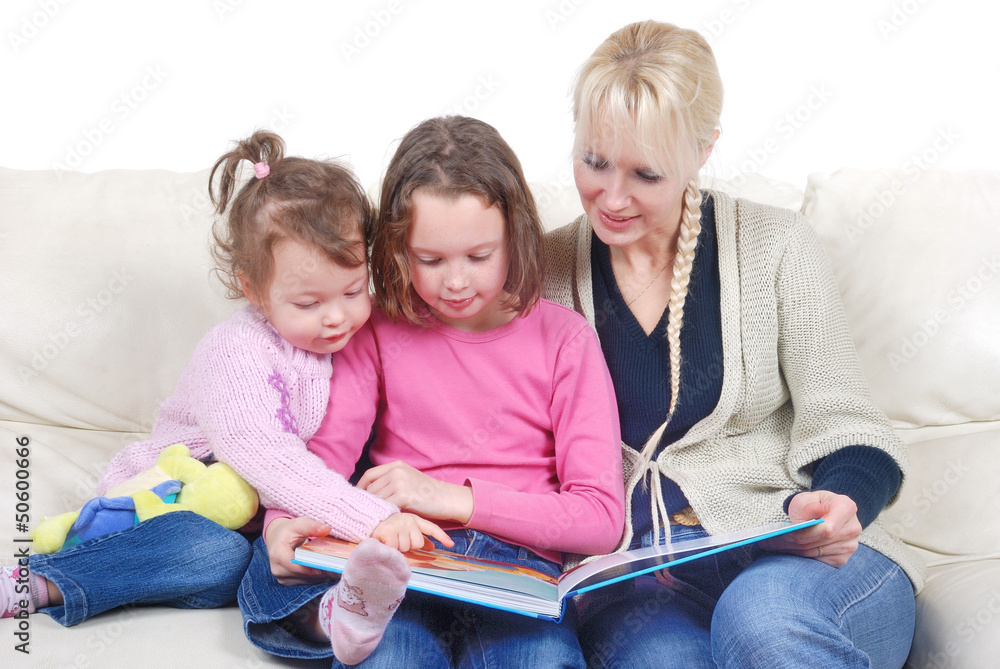 Mother and children sitting in living room reading book