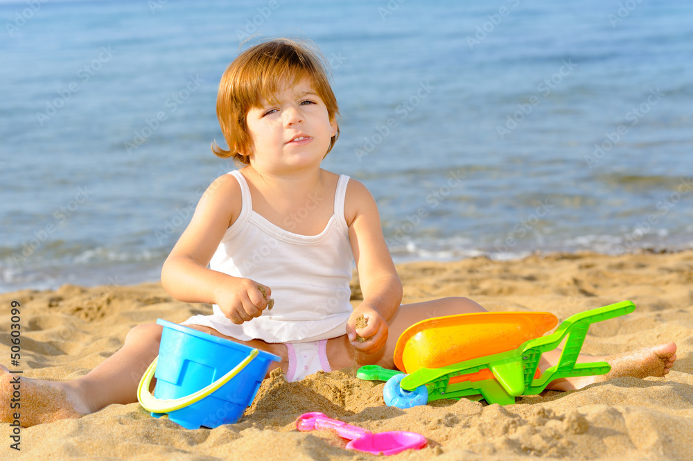 Happy toddler girl playing with her toys at beach Happy toddler girl playing with her toys at beach