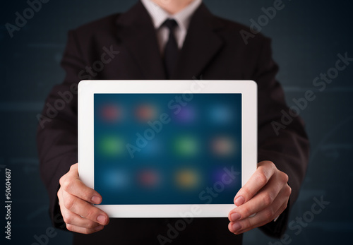 Wallpaper Mural Businessman holding a white modern tablet with blurry apps Torontodigital.ca