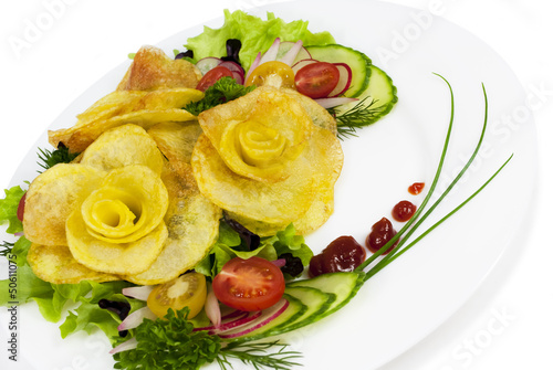 French fries in the form of a rose on a plate with a salad on wh