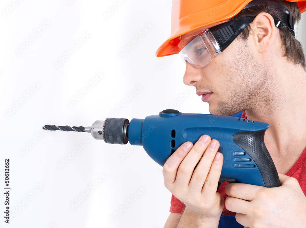 A man drilling a hole in the wall. A man drilling a hole in the wall.