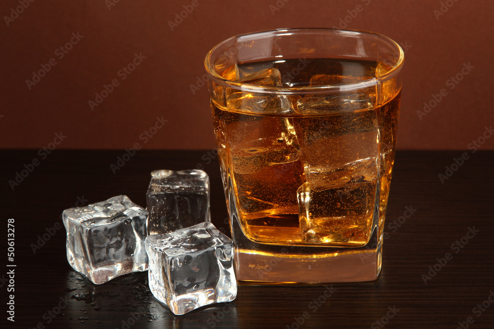Glass of whiskey and ice on brown background Glass of whiskey and ice on brown background