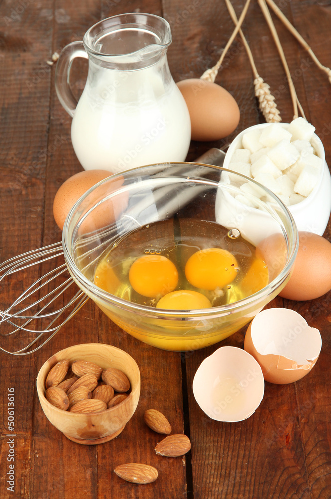 Broken egg in bowl and various ingredients next to them Broken egg in bowl and various ingredients next to them