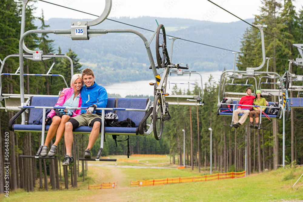 Smiling couples using chair lift scenic landscape Smiling couples using chair lift scenic landscape