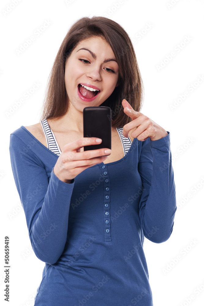Excitement woman with mobile phone pointing at camera Excitement woman with mobile phone pointing at camera