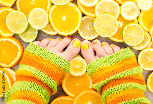 Female legs between citrus fruits