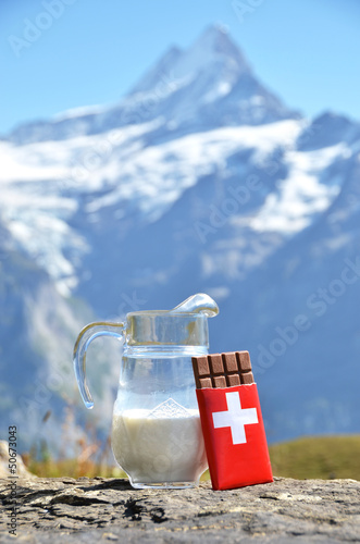 Swiss chocolate and jug of milk against mountain peak. Switzerla photo