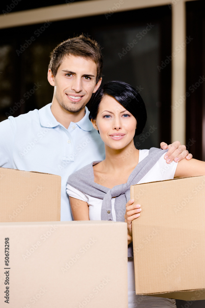 Couple carrying pasteboard packages while moving to new house Couple carrying pasteboard packages while moving to new house