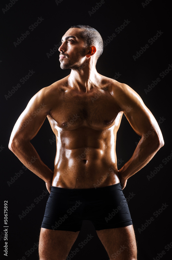 Muscular man in dark studio Muscular man in dark studio
