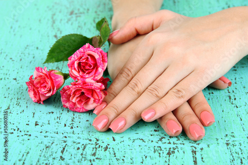 Woman hands with pink manicure and flowers  on color background