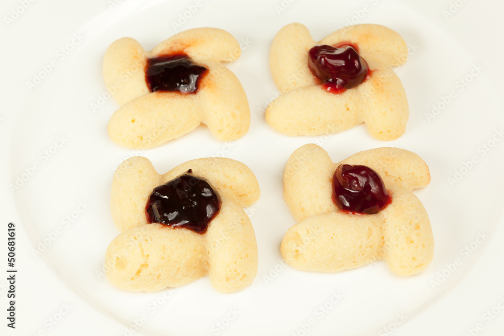 Four cookies with preserved cherry in center on plate Four cookies with preserved cherry in center on plate