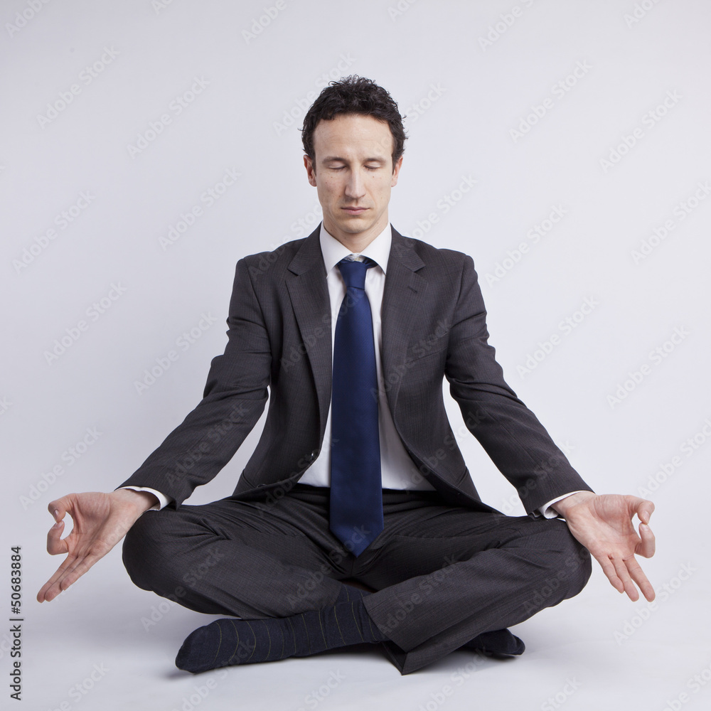 young businessman meditating in yoga lotus pose on white backgro young businessman meditating in yoga lotus pose on white backgro