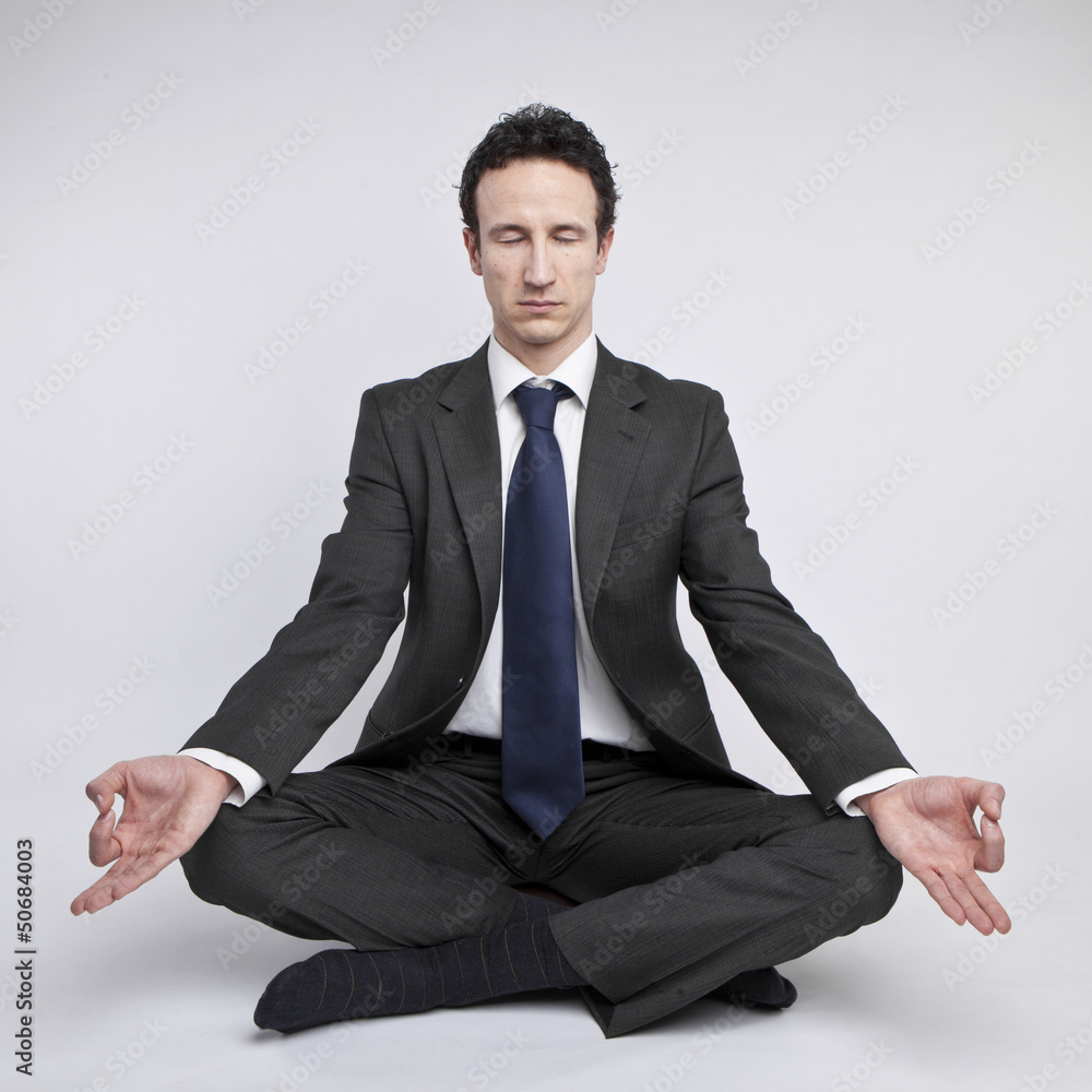 young businessman meditating in yoga lotus pose on white backgro young businessman meditating in yoga lotus pose on white backgro