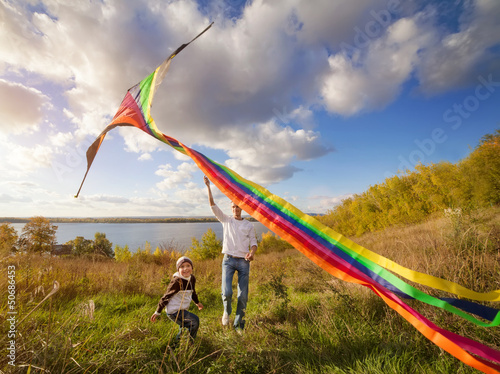 father with son in autumn playing with kite