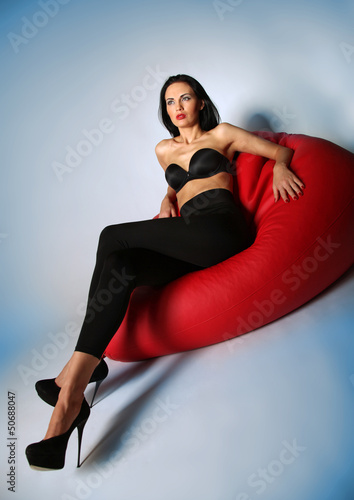 Sexy brunette Beauty sitting on a red armchair