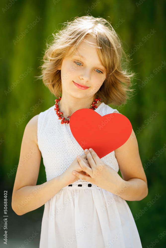 Lovely pensive girl holding heart shape outdoors Lovely pensive girl holding heart shape outdoors