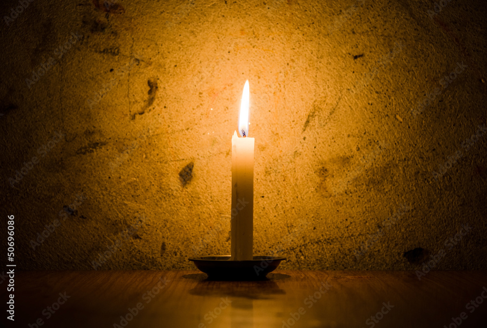 Candle burning, grungy wall background