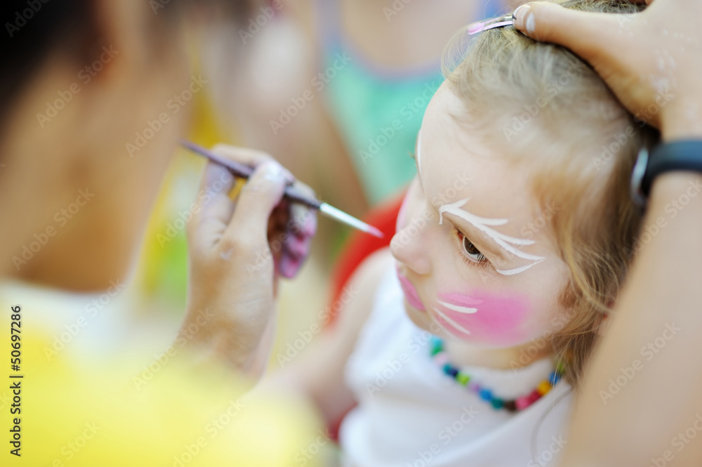 Naklejka premium Adorable girl getting her face painted