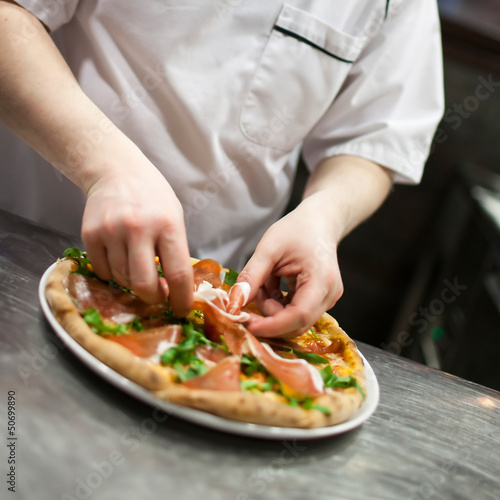 Fototapeta Naklejka Na Ścianę i Meble -  Closeup hand of chef baker in white uniform making pizza at kitc