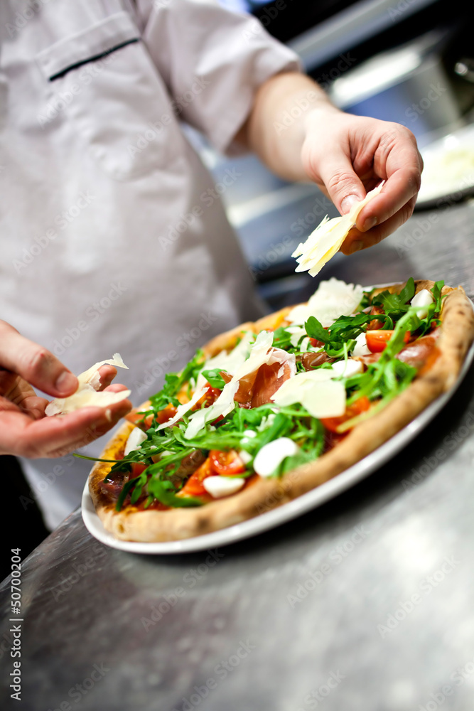 Closeup hand of chef baker in white uniform making pizza at kitc