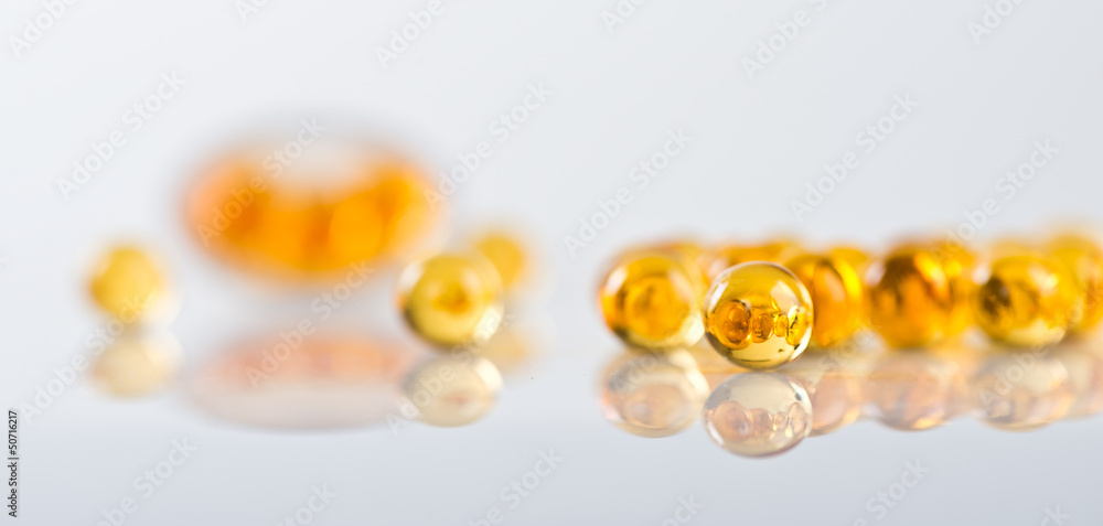 Capsules of fish oil spilled out open container Capsules of fish oil spilled out open container