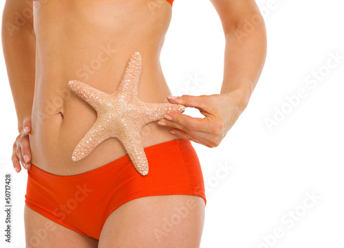 Closeup on starfish in hand of young woman in swimsuit